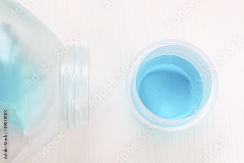 Fototapeta Naklejka Na Ścianę i Meble -  Laundry gel in a transparent bottle and a measuring cup. Blue wash gel.