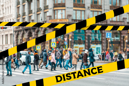 Do not cross.Barrier tape-quarantine,isolation. In the blur of the intersection where a group of people cross the street on the background of the building.The concept of coronavirus and quarantine