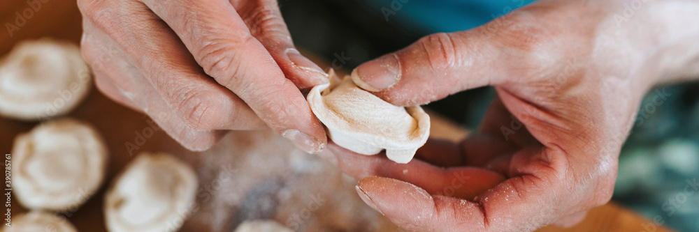 hands of senior man cooking and molding small homemade uncooked dumplings with meat on kitchen table. national traditional Russian cuisine. do it yourself. top view. banner hands of senior man cooking and molding small homemade uncooked dumplings with meat on kitchen table. national traditional Russian cuisine. do it yourself. top view. banner