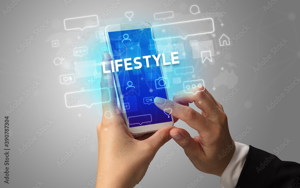 Female hand typing on smartphone with LIFESTYLE inscription, social media concept Female hand typing on smartphone with LIFESTYLE inscription, social media concept