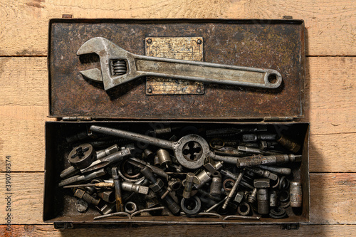 Old vintage iron toolbox full of drills and threading die tools on a wooden background