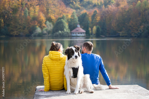 Couple in love with dog relaxing at the lake.