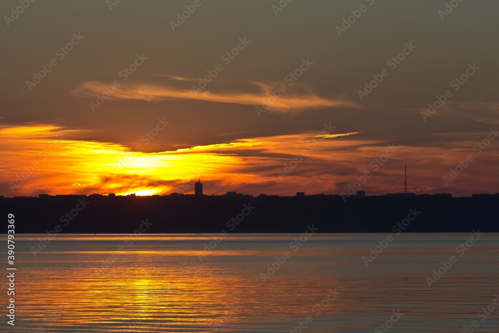 A sunset over the Volga river and Russian city Ulyanovsk. Cirrus dark clouds and silhouette of buildings.