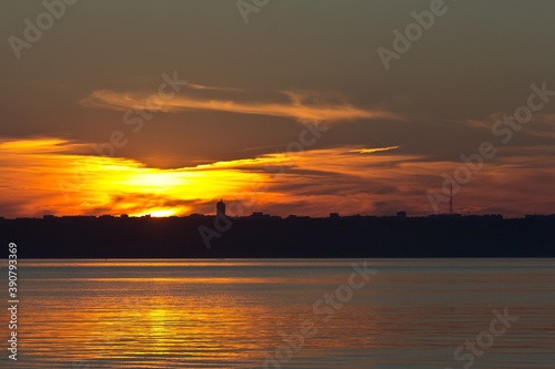 A sunset over the Volga river and Russian city Ulyanovsk. Cirrus dark clouds and silhouette of buildings.