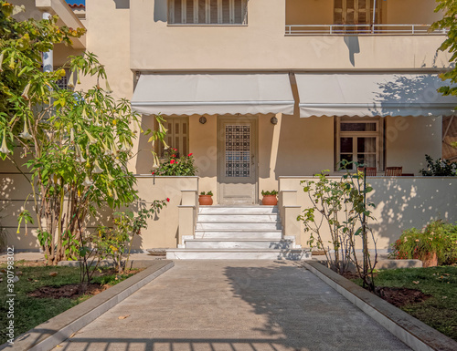 Fototapeta Naklejka Na Ścianę i Meble -  cozy family house front marble stairs to entrance door with flowerpots, Athens Greece