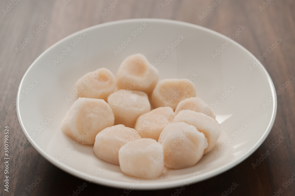 frozen scallops in white bowl on walnut table for defrosting frozen scallops in white bowl on walnut table for defrosting