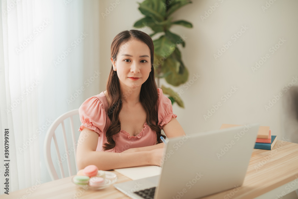 smiling asian woman working with laptop on table in white interior home office smiling asian woman working with laptop on table in white interior home office