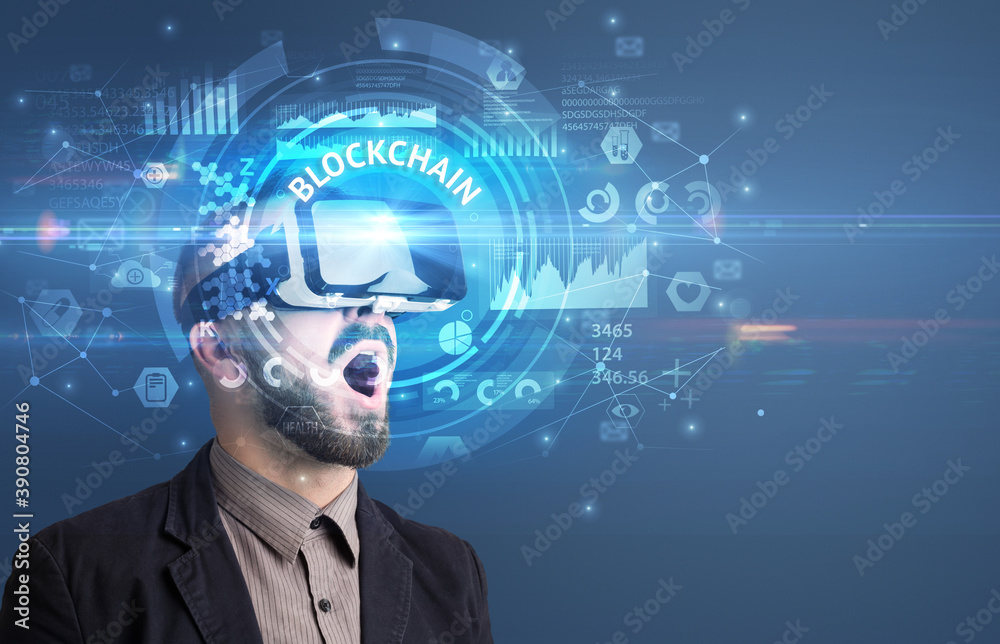 Businessman looking through Virtual Reality glasses with BLOCKCHAIN inscription, innovative technology concept Businessman looking through Virtual Reality glasses with BLOCKCHAIN inscription, innovative technology concept