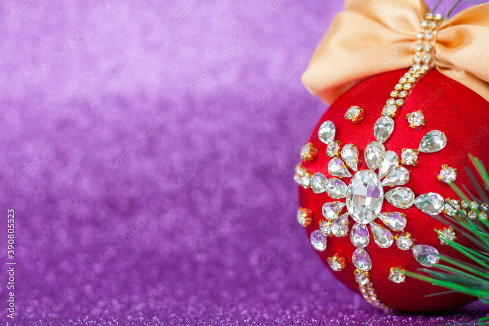 Red Christmas ball in rhinestones for Christmas tree decoration. Christmas toy. Christmas toy for decorating a Christmas tree on a lilac background. Shining crystals on a red ball.