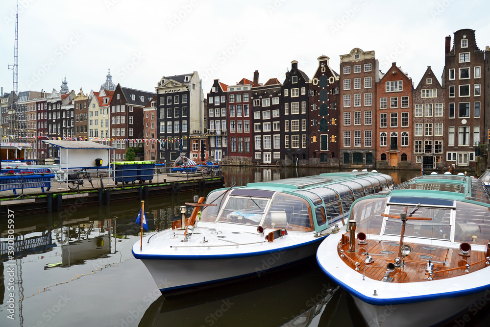 Famous vintage buildings of Amsterdam city. General landscape view at tradition Dutch architecture. Damrak canal in Amsterdam, The Netherlands.