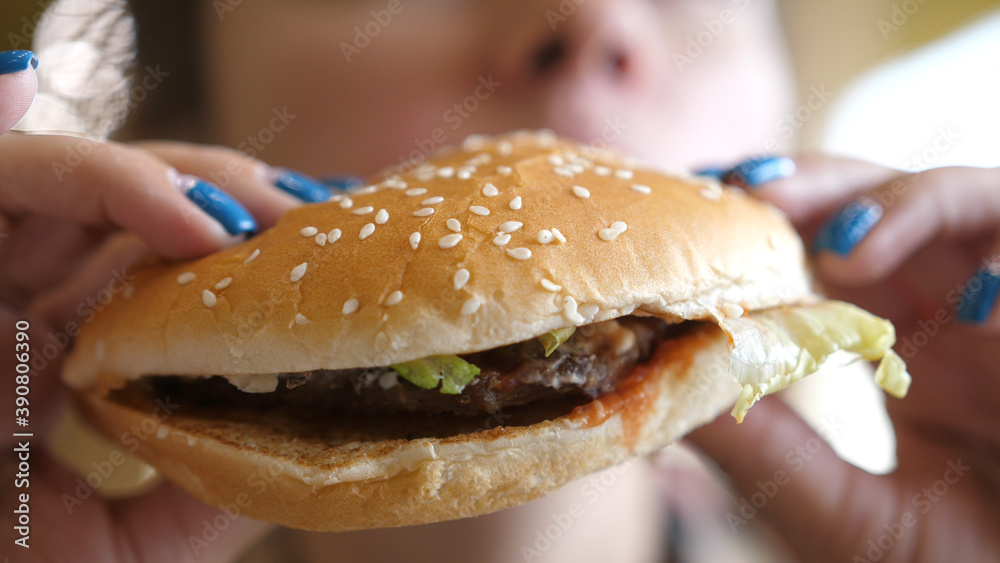 Girl eating a hamburger. close-up shot. Fast food eats. Burger in female hands.