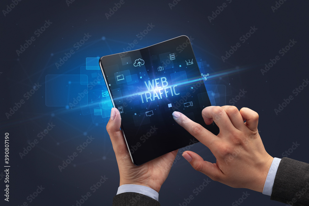 Businessman holding a foldable smartphone with WEB TRAFFIC inscription, cyber security concept Businessman holding a foldable smartphone with WEB TRAFFIC inscription, cyber security concept