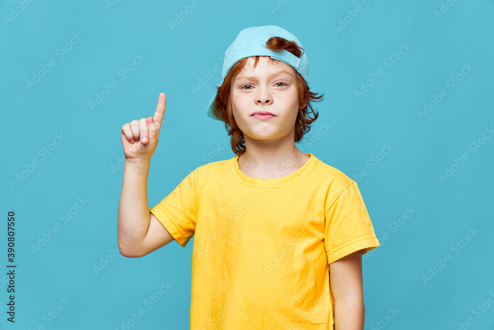redhead boy in blue cap cropped points finger up
