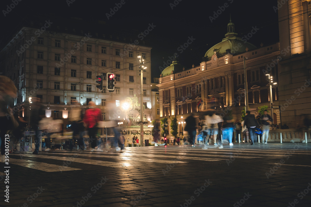 Pedestrian crossing in the historic center of Belgrade, blurred figures of people in the night city