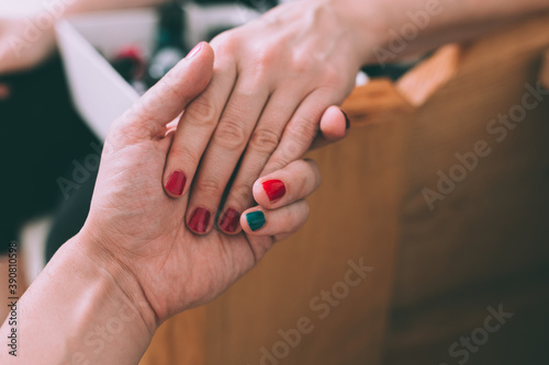 Man and woman having painted nails  holding hands. Close up shot.