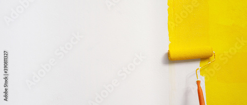 Roller Brush Painting, Worker painting on surface wall  Painting apartment, renovating with yellow color  paint. Leave empty copy space white to write descriptive text beside. photo