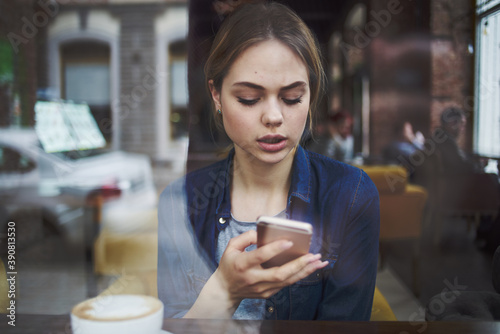 Woman communicates on the phone of a cafe at the table with a cup of coffee in the morning lifestyle