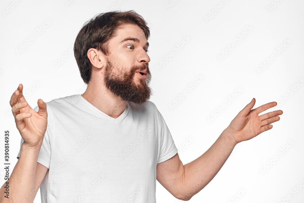 cheerful bearded man in a white t-shirt emotions gestures with his hands light background studio cheerful bearded man in a white t-shirt emotions gestures with his hands light background studio