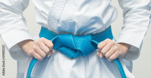 hands grabbing blue karate belt