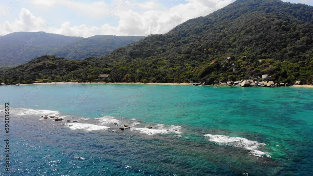 Aerial view low over the sea, on the coast of Tayrona national natural park, sunny day, in Caribbean Colombia, South America - tracking, pan, drone shot Aerial view low over the sea, on the coast of Tayrona national natural park, sunny day, in Caribbean Colombia, South America - tracking, pan, drone shot