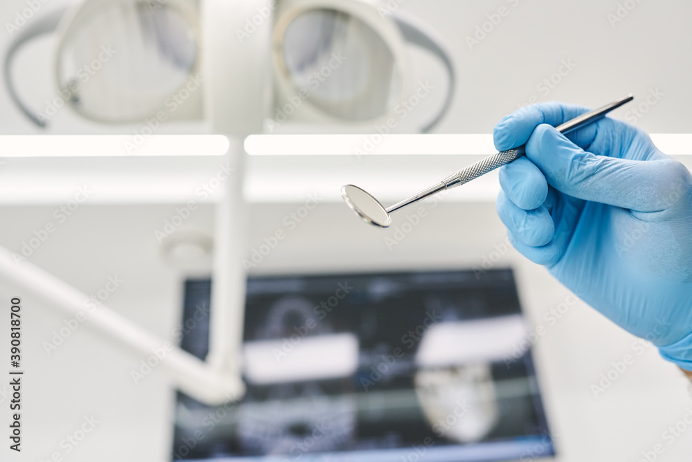 Hand of a dentist in a blue latex glove holds a tool. Bottom view. Hand of a dentist in a blue latex glove holds a tool. Bottom view.
