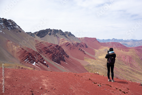 A woman enjoying the view of the red mountains near the rainbow mountain   winicunca   near the city of cusco - Peru