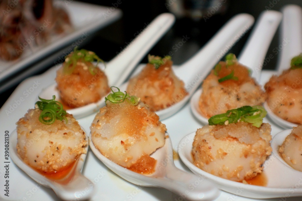 Appetizers in small white spoons, with green onions on top