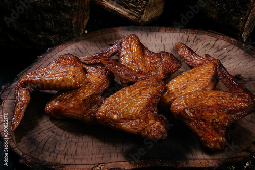 Smoked chicken wings on a dark wooden background close up.