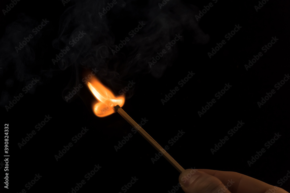 A lighted match on a black background. Hold a lighted match. The fire from the match illuminates everything around. Arson, danger, flash. Macro fire burning on matchstick. Idea, concept, A lighted match on a black background. Hold a lighted match. The fire from the match illuminates everything around. Arson, danger, flash. Macro fire burning on matchstick. Idea, concept,