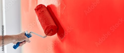Fototapeta Naklejka Na Ścianę i Meble -  Male hand painting wall with paint roller. Painting apartment, renovating with red color paint
