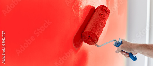 Fototapeta Naklejka Na Ścianę i Meble -  Male hand painting wall with paint roller. Painting apartment, renovating with red color paint