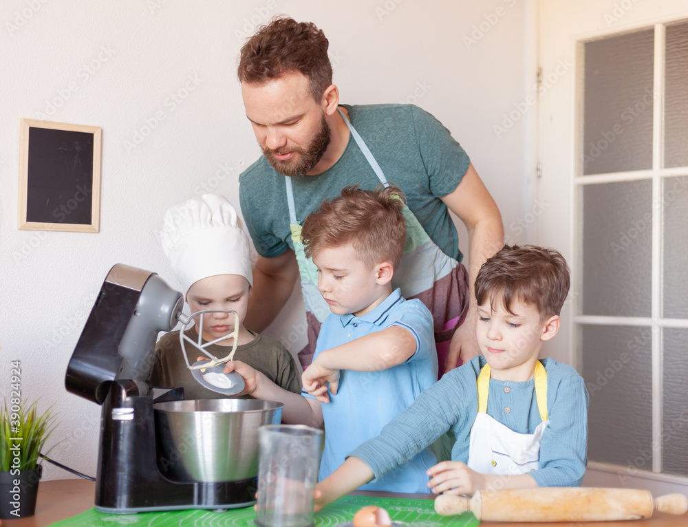 happy father with children cooks on paternity leave in the kitchen happy father with children cooks on paternity leave in the kitchen