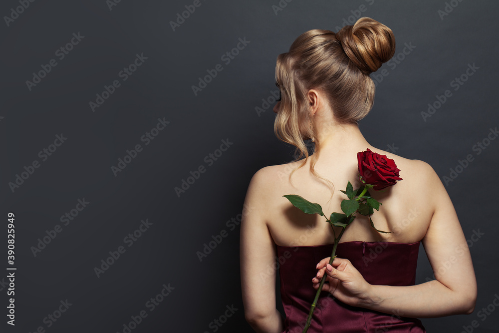 Beautiful woman back head with blonde hair updo hairdo holding red rose flower on black Beautiful woman back head with blonde hair updo hairdo holding red rose flower on black