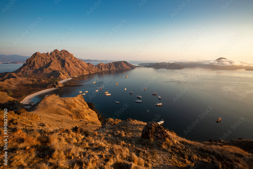Sunrise over mountains and sea with sailing ships at Rinca (Komodo National Park) 