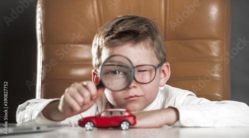 Child car expert. Kid with big magnifying glass observing a toy car. Businessman choose a car