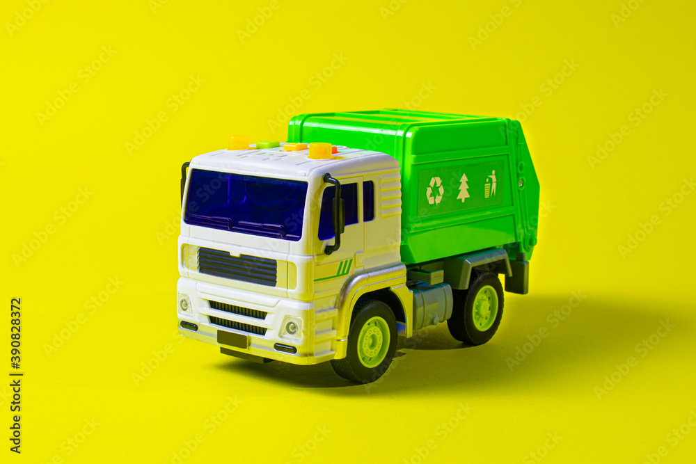 The toy garbage truck white-green with a yellow background. Children's toy car with buttons. For the toy store The toy garbage truck white-green with a yellow background. Children's toy car with buttons. For the toy store