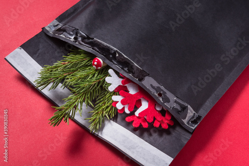 Black bubble envelope decorated with christmas tree ornament on red background