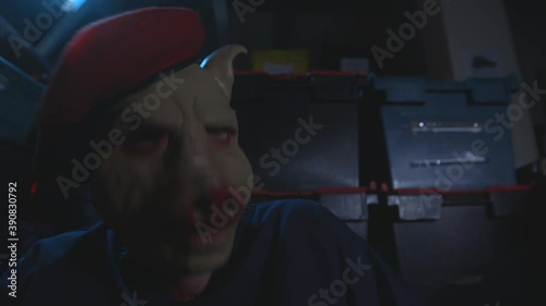 Man in pig mask suddenly wakes up and hyperventilates in a warehouse photo