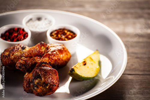 Barbecue chicken drumsticks with fried pear on wooden table 