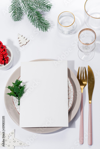 Winter festive table setting with cutlery and white brochure on table. Christmas tableware.