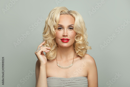Attractive woman celebrity with makeup and blonde curly hair on white background