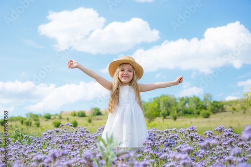 a little girl in a straw hat in a field of purple flowers rejoice