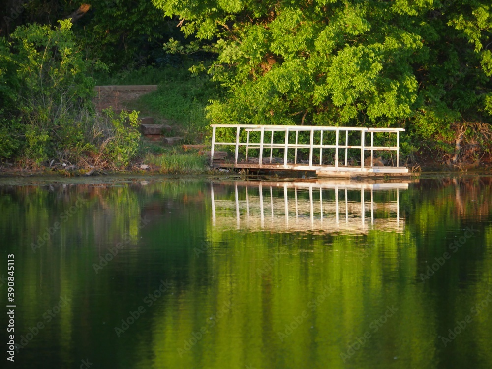 White floating dock reflected in the waters of a lake one spring morning White floating dock reflected in the waters of a lake one spring morning