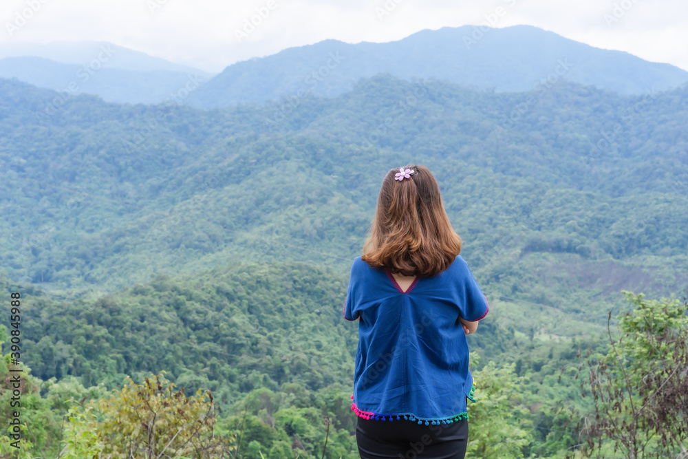 Back view of lonely freedom traveler adult woman standing on the top view of mountains enjoying beautiful nature sunrise and relaxing in the mountains at sunset at Nan, Thailand. Positive concept