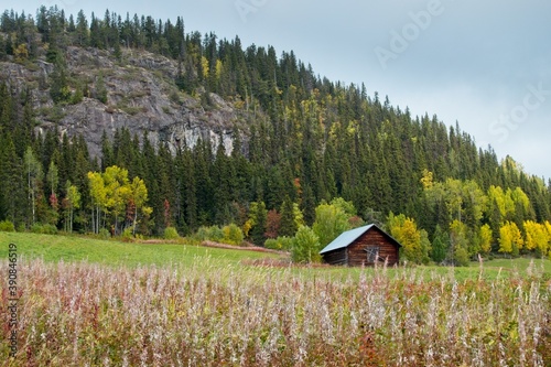 Wooden Scandinavian barn in the field near the hill