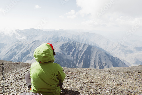 Woman hiker in green jacket enjoying mountains view. Active lifestyle concept.