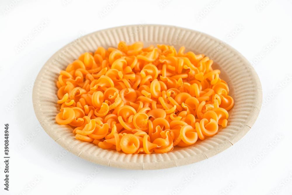 Orange pasta in a disposable paper plate on a white background. Top view. Copy, empty space for text Orange pasta in a disposable paper plate on a white background. Top view. Copy, empty space for text