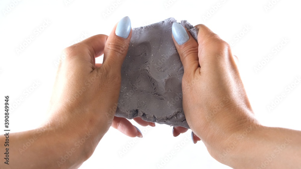 Fototapeta premium Female hands are molded from silver gray blue plasticine, developing activities for children.