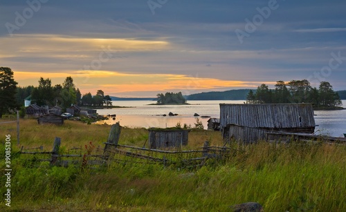Rural area in summer in North Karelia, Russia. Small wooden houses on the bank of the White sea against colorful sunset. © Алексей Мараховец