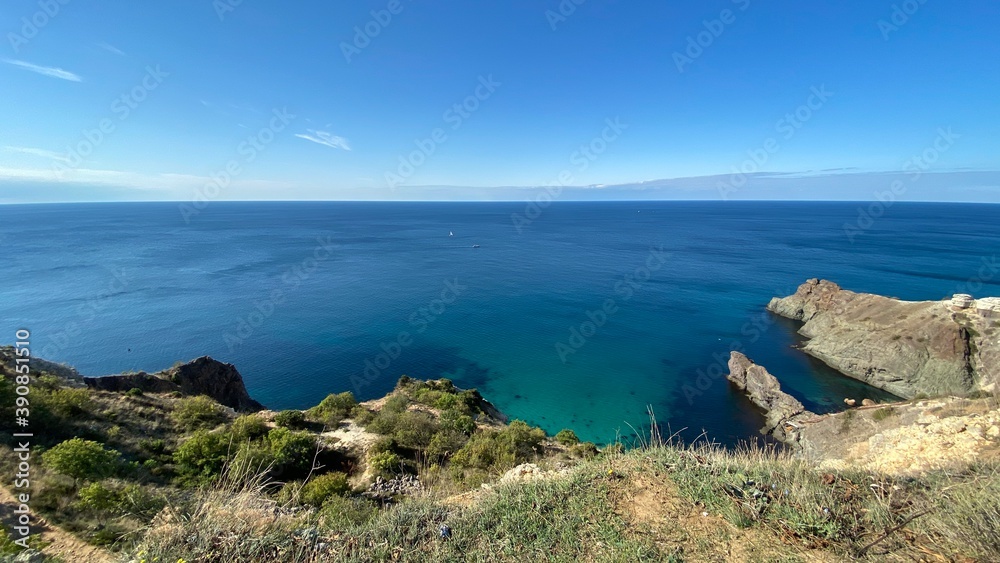 Panoramic seascape - calm azure sea, horizon, rocks and mountains surround the Black Sea bay in Crimea, Cape Fiolent in Sevastopol.